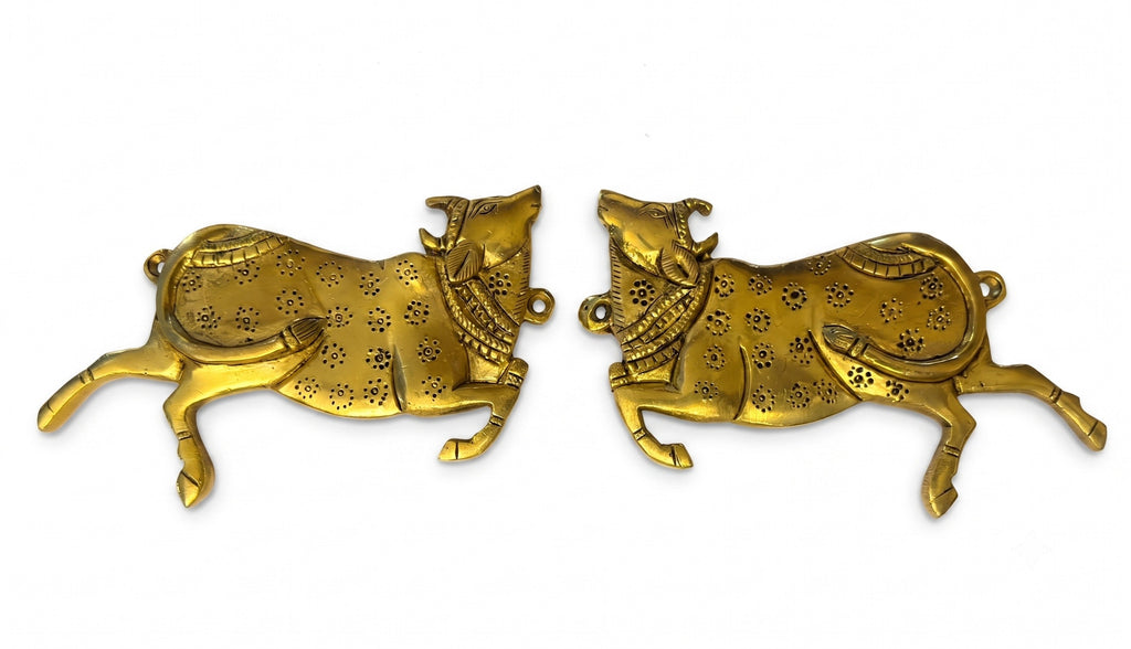 Svarn Studio Brass Sacred Cow Wall Hanging Set of 2 - Lifestyle in grand marble foyer with wooden door, brass diya and marigold flowers on console